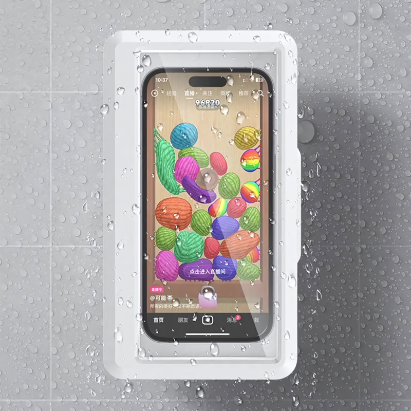 Dans une salle de bain ou une douche, un smartphone est solidement fixé sur un mur carrelé dans la coque étanche blanche PhonoNest™ de Homesafetouch, offrant une étanchéité à 360°. L'écran du téléphone affiche un jeu coloré avec des formes et des chiffres variés, tandis que des gouttes d'eau sont visibles sur la coque, indiquant qu'elle reste fonctionnelle dans des conditions humides.